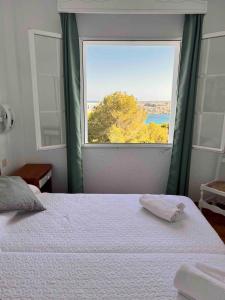 um quarto com uma cama e uma grande janela em Apartamento 107 Castell Sol CB em Arenal d'en Castell