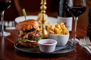 een hamburger en frietjes op een tafel met wijnglazen bij Martin Arms in Colston Bassett