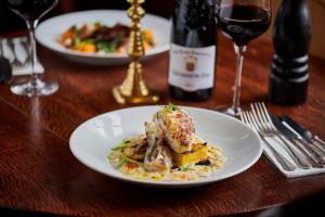 Martin Arms في Colston Bassett: طاولة مع طبقين من الطعام وزجاجة من النبيذ