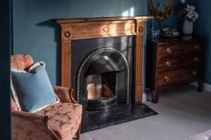 a fireplace in a room with a chair and a dresser at Martin Arms in Colston Bassett