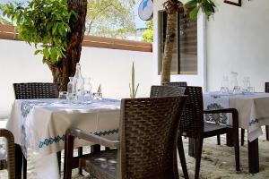 uma sala de jantar com mesas e cadeiras e uma árvore em Manta Sky Inn em Dharavandhoo