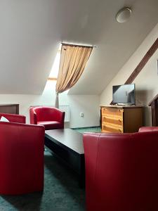 a living room with red chairs and a flat screen tv at Hotel GEO in Prague