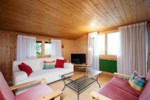 ein Wohnzimmer mit einem weißen Sofa und einem TV in der Unterkunft Apartment im Chalet Sidonie in Amden
