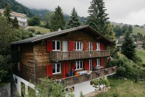 uma casa de madeira com uma varanda numa colina em Apartment im Chalet Sidonie em Amden