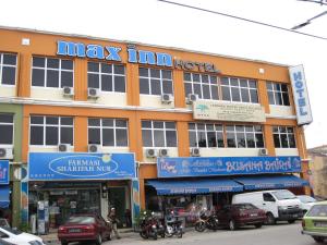 een groot gebouw met auto's geparkeerd voor het bij Max Inn Hotel in Parit Raja
