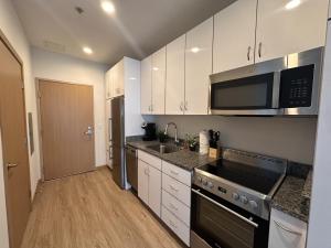 uma cozinha com armários brancos, um lavatório e um micro-ondas em Flexhome East Side 1BR R2 - Brady Fiserv Balcony - READ INFO em Milwaukee