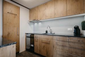 una cocina con armarios de madera y fregadero en Apartment Bergdohle, en Amden