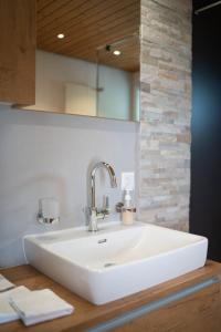 lavabo blanco en el baño con espejo en Apartment Bergdohle, en Amden