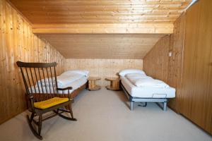 Cette chambre comprend 2 lits et une chaise. dans l'établissement Chalet Chapfwald, à Amden