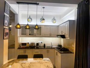 a kitchen with white cabinets and a table with chairs at AWHILE CASA in Nuwara Eliya