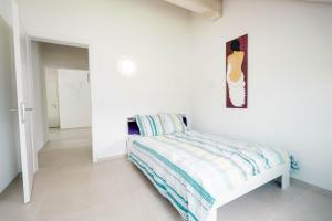 a white bedroom with a bed and a painting on the wall at Apartment Soldanella in Amden