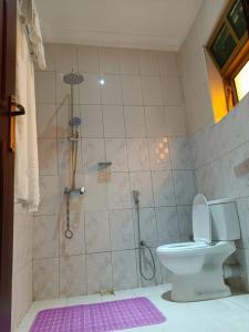 łazienka z prysznicem, toaletą i fioletowym dywanem w obiekcie Beri Cottages w mieście Arua