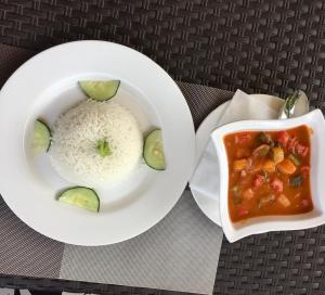 a plate of rice and a bowl of food with cucumbers at Beri Cottages in Arua