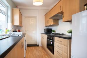 uma cozinha com armários de madeira e um balcão preto em 4Bedrooms-3Bath-9Beds-Wallsend em Old Walker