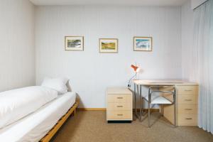 a bedroom with a bed and a desk and a bed and a table at Apartment Morgensonne in Amden