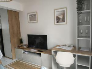 uma sala de estar com uma secretária, uma televisão e uma cadeira em Tresor de Beaurains em Beaurains