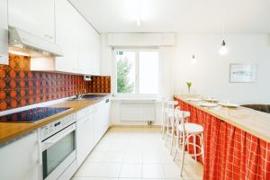 a kitchen with white cabinets and red tiles at Apartment Morgensonne in Amden