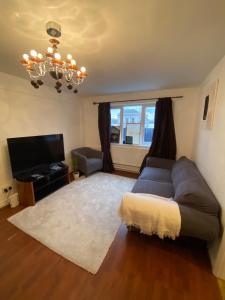 a living room with a couch and a television at Well Located 2BD Flat 20 Mins to Tower Bridge! in London