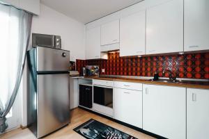 uma cozinha com armários brancos e um frigorífico de aço inoxidável em Apartment Panoramablick em Amden