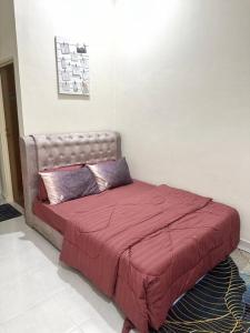 een bed met een rode deken en kussens in een kamer bij D'Banggol Homestay in Ketereh