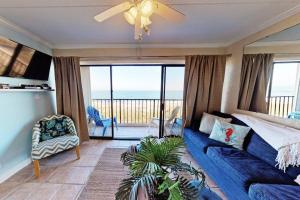 a living room with a blue couch and a view of the ocean at Paradise Found in Carolina Beach
