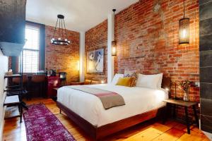 Un dormitorio con una pared de ladrillo y una cama en Edison's Inn and The Perth County Inn - 2 Beautiful Boutique Inns on the Same Block en Stratford