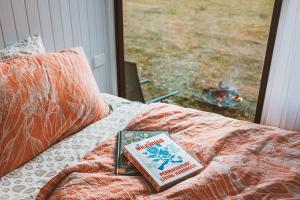 een boek bovenop een bed met een raam bij Pine Edge Heights in Ellendale
