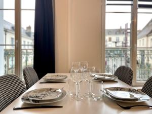 a table with glasses and plates on it with a window at Le repère secret de Nestor - SOnights in Château-du-Loir