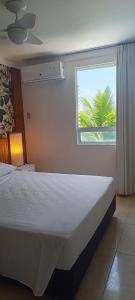 a bedroom with a bed and a window with a palm tree at Beira-Mar flat 310 Ponta Negra Beach in Natal