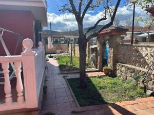 a house with a white fence and a tree at Chalet vacacional en Pelayos in Pelayos de la Presa