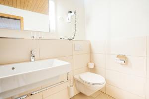 Baño blanco con lavabo y aseo en Apartment Bischofberger D20, en Amden