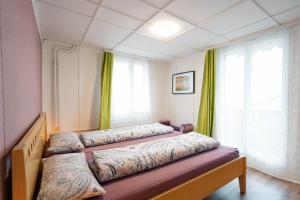 2 camas en una habitación con cortinas verdes en Apartment Heimathus, en Amden