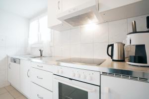 - une cuisine blanche avec cuisinière et évier dans l'établissement Apartment im Chalet Biodola, à Amden
