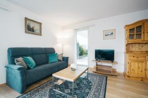 ein Wohnzimmer mit einem blauen Sofa und einem TV in der Unterkunft Apartment Im Aeschen in Amden