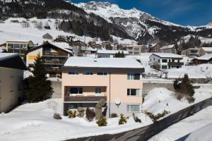 a building in the snow with mountains in the background at Apartment Im Aeschen in Amden