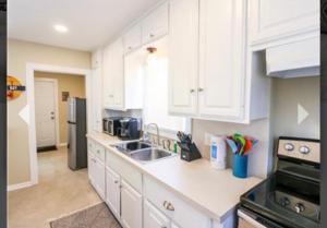 a kitchen with white cabinets and a sink and a refrigerator at Old Bay All Day in Galveston