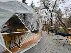 a tent on a deck with a table and chairs at Enchanted Forest Dome ,10-15 minutes to Kings Canyons in Dunlap