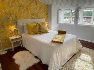 een slaapkamer met een wit bed met geel behang bij Yellow Home in Santiago de Compostela