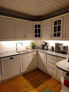 een keuken met witte kasten en een wastafel bij Koselig overnattingssted med fjordutsikt in Sjøvegan