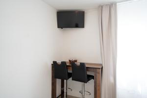 a dining room table with chairs and a television on the wall at Haus Gmür Amden Erdgeschoss in Amden