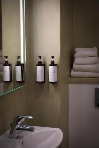 uma casa de banho com três garrafas de sabão na parede em Frederiksdal Sinatur Hotel & Konference em Kongens Lyngby