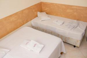 two beds in a small room with white sheets at Pousada Santa Cruz in Aparecida