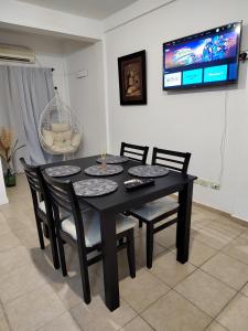 mesa de comedor negra con sillas y TV en Dpto Nuevocentro Shopping en Córdoba