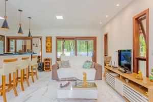 a living room with a white couch and a kitchen at PF26 Excelente Casa 4 Suítes - Praia do Forte in Mata de Sao Joao