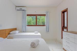 two beds in a white room with a window at PF26 Excelente Casa 4 Suítes - Praia do Forte in Mata de Sao Joao +43 photos