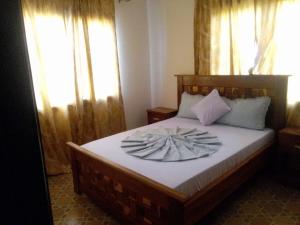 a bedroom with a bed with a flower on it at BARAKAH ESTATE APARTMENTS in Sere Kunda