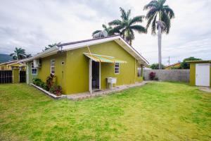 uma casa amarela com uma palmeira no quintal em Ocho Rios Drax Hall Country Club 2 Bed Villa Getaway em Mammee Bay