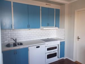 a kitchen with blue cabinets and a sink at Bed & Breakfast de Jager in Strömsbruk