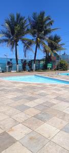 a swimming pool with two palm trees and the ocean at Beira-Mar flat 310 Ponta Negra Beach in Natal