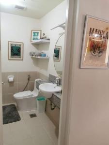 een badkamer met een wastafel, een toilet en een spiegel bij 2BR Penthouse in Brixton Place with breathtaking view of BGC in Manilla